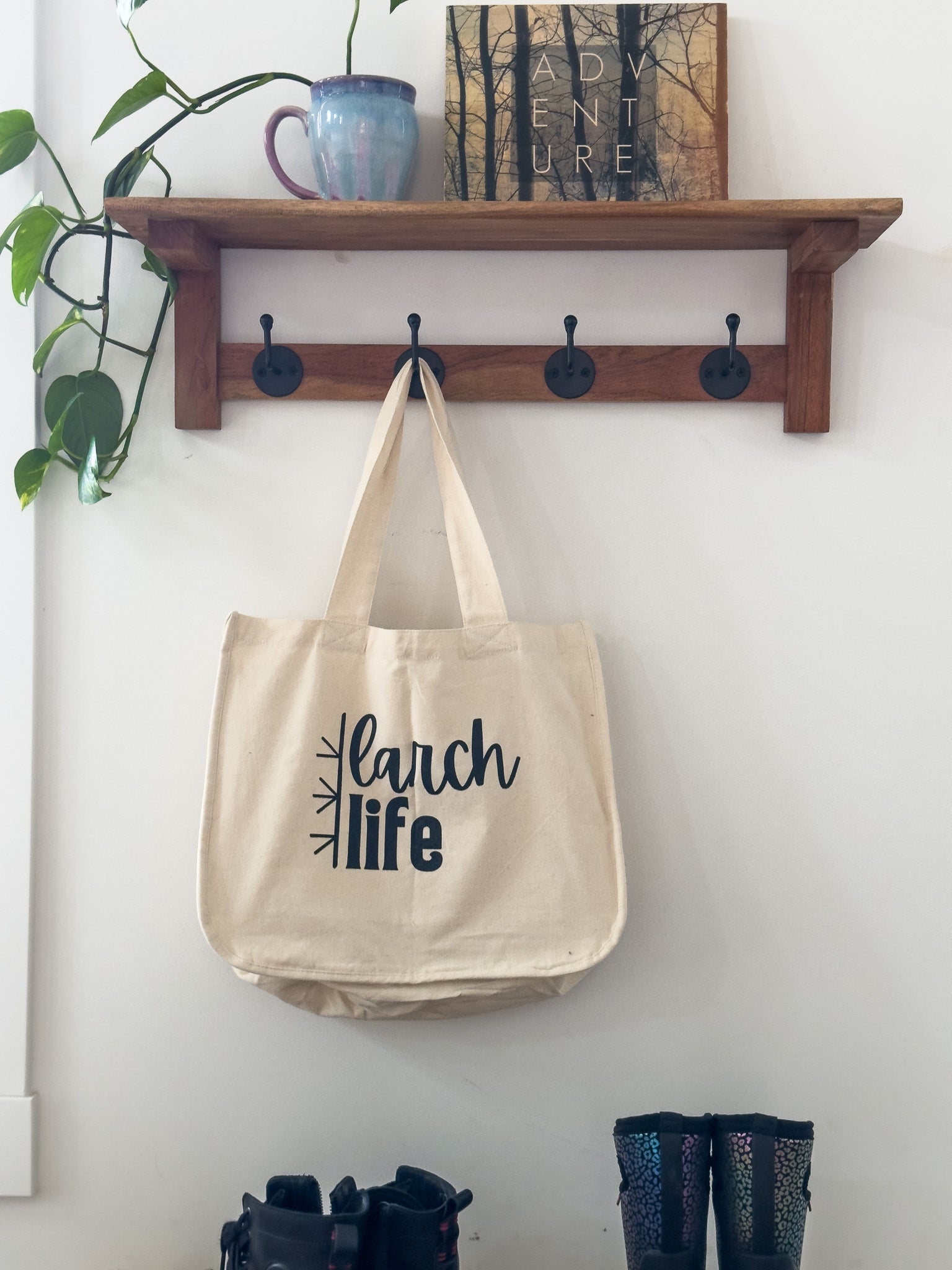 An eco-friendly Larch Life multi-pocket tote bag hangs on a hook