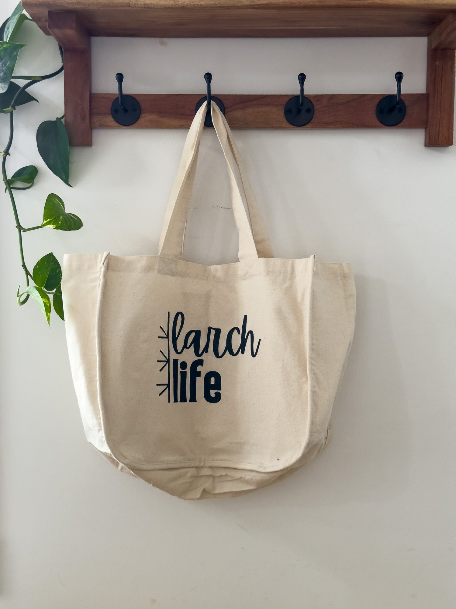 An eco-friendly Larch Life multi-pocket tote bag hangs on a hook