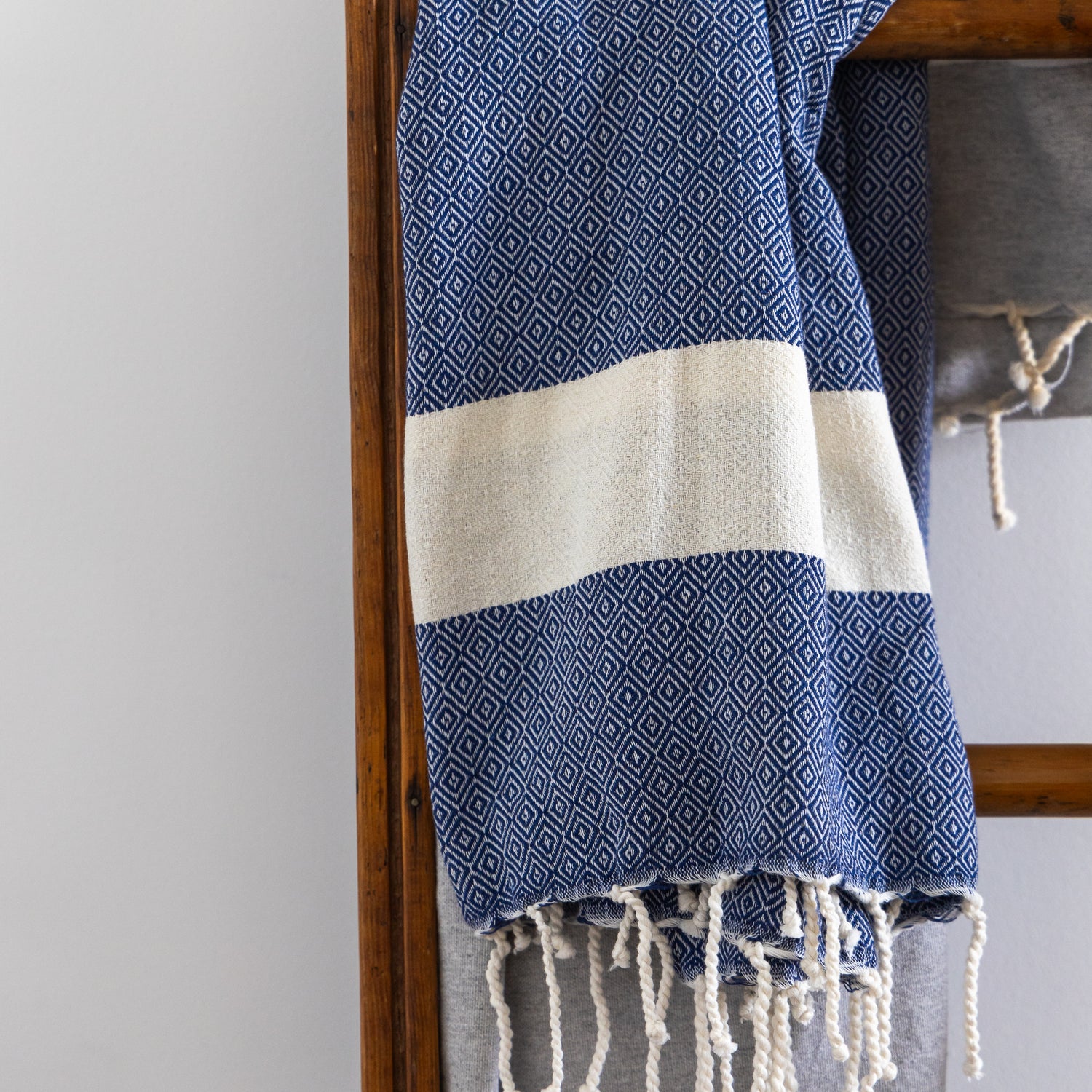 A blue natural cotton Turkish towel hangs on a ladder