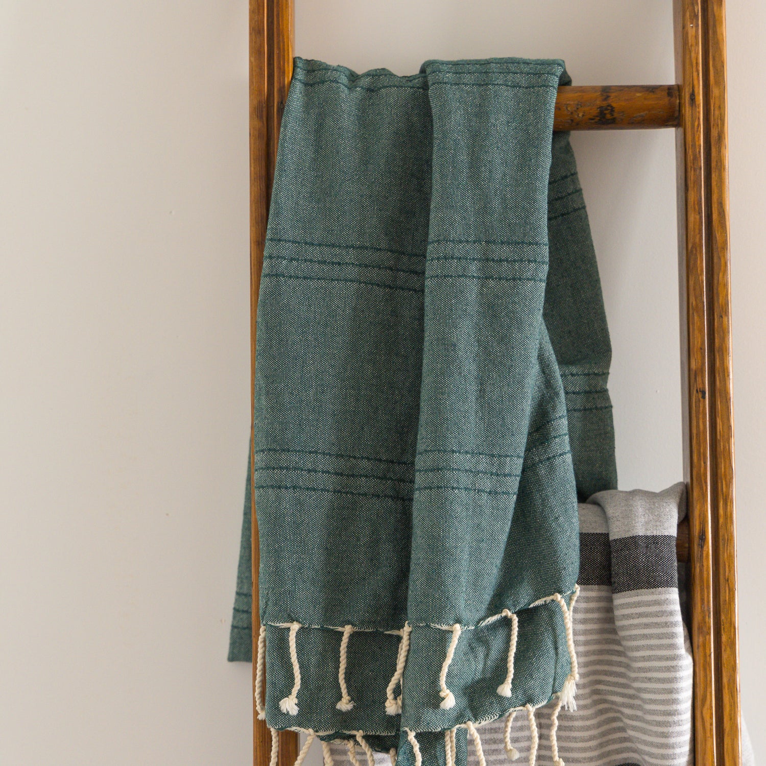 A green natural cotton Turkish towel hangs on a ladder