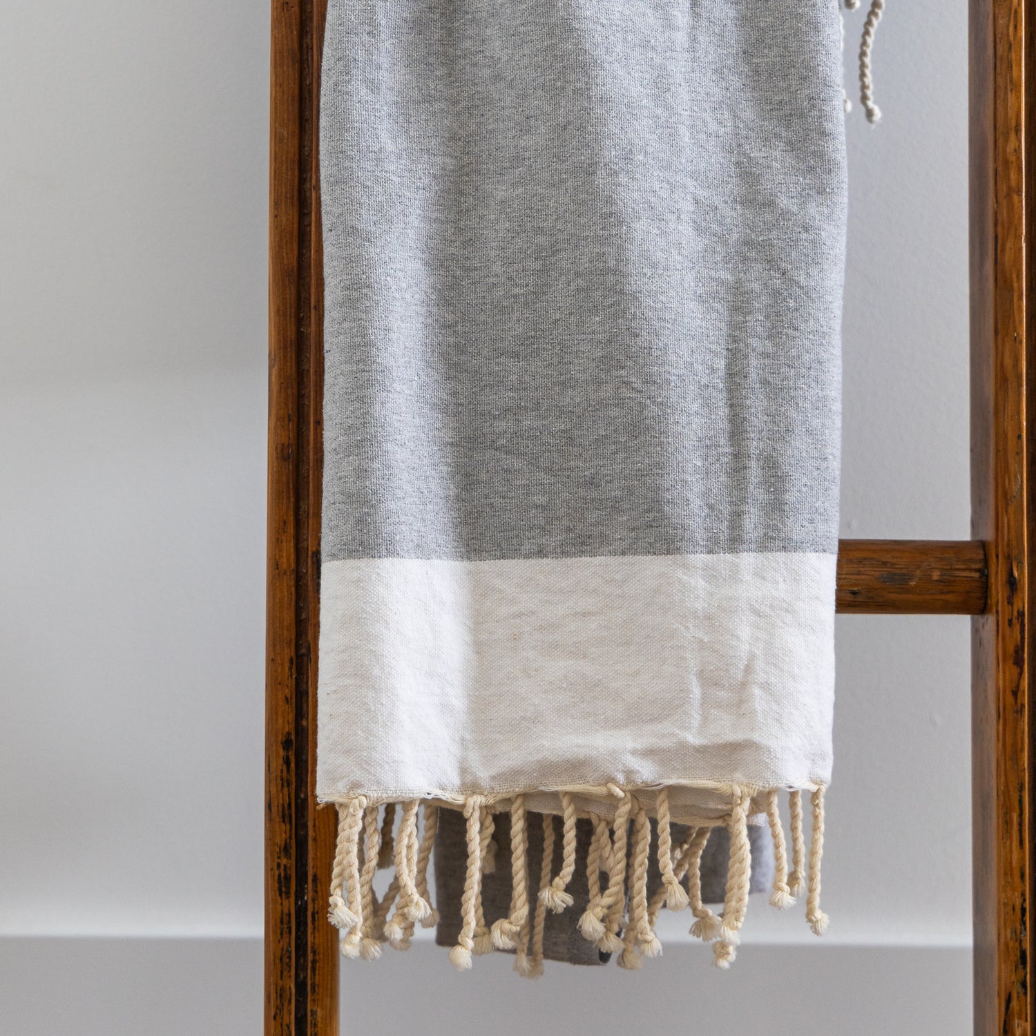 A light grey natural cotton Turkish towel hangs on a ladder