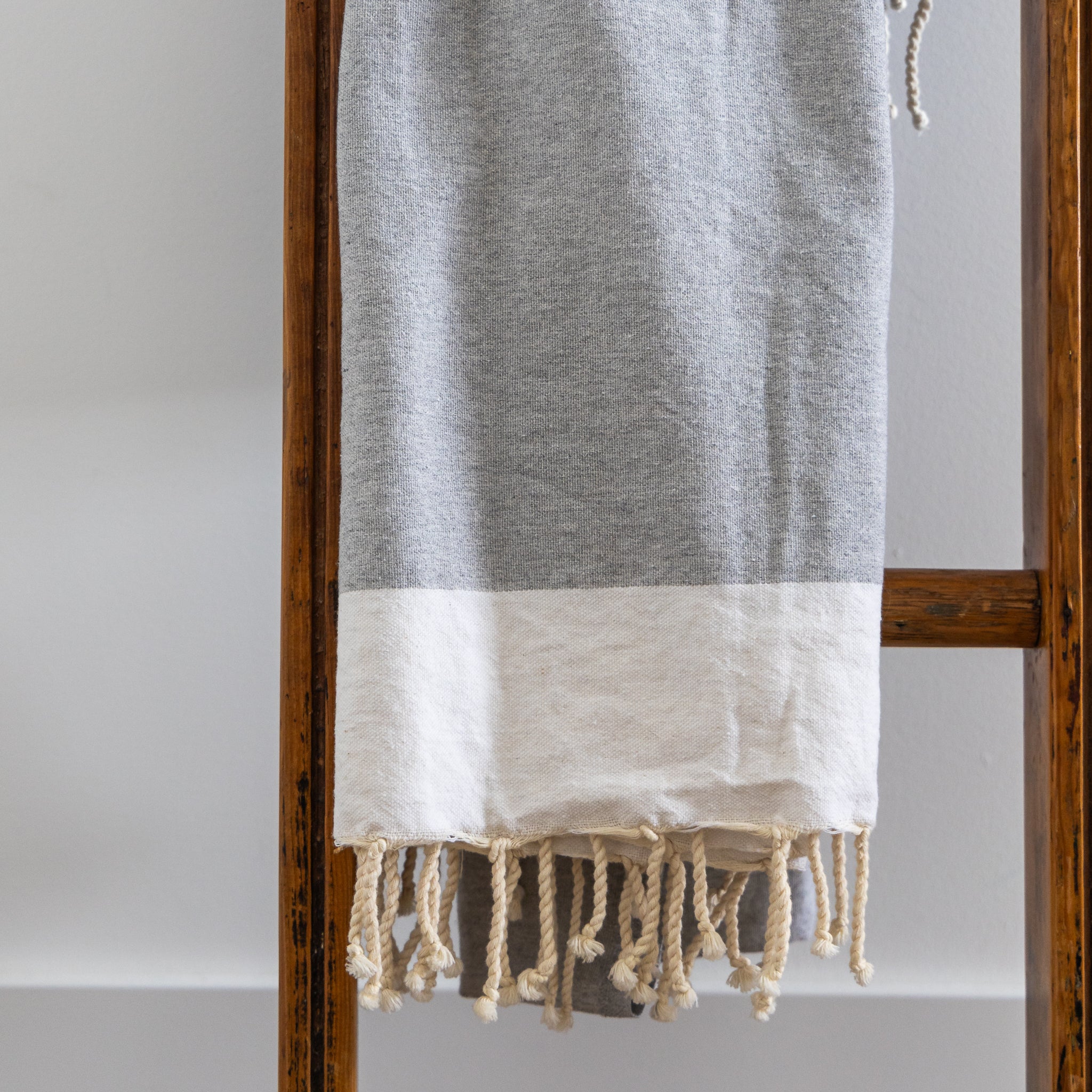 A light grey natural cotton Turkish towel hangs on a ladder