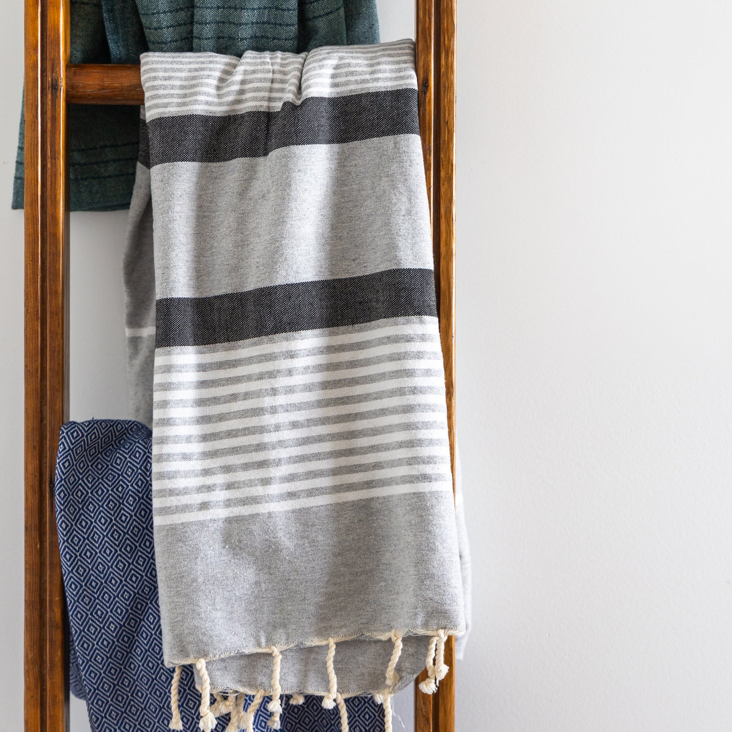 A grey and white striped natural cotton Turkish towel hangs on a ladder