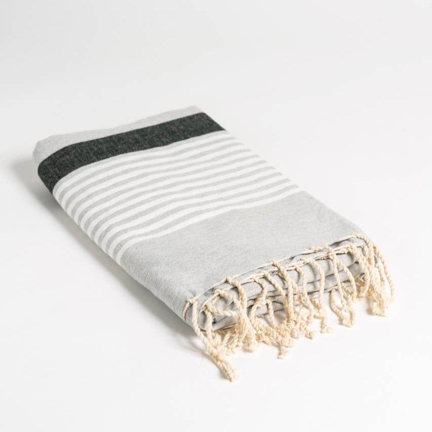 A grey and white striped natural cotton Turkish towel lays folded