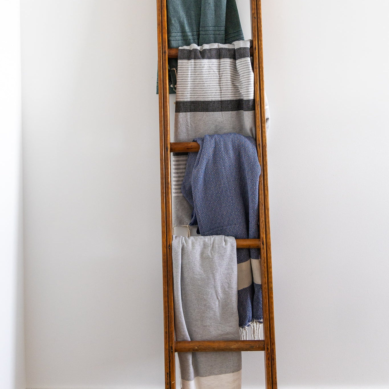 Four colours of Turkish towels hang on a ladder