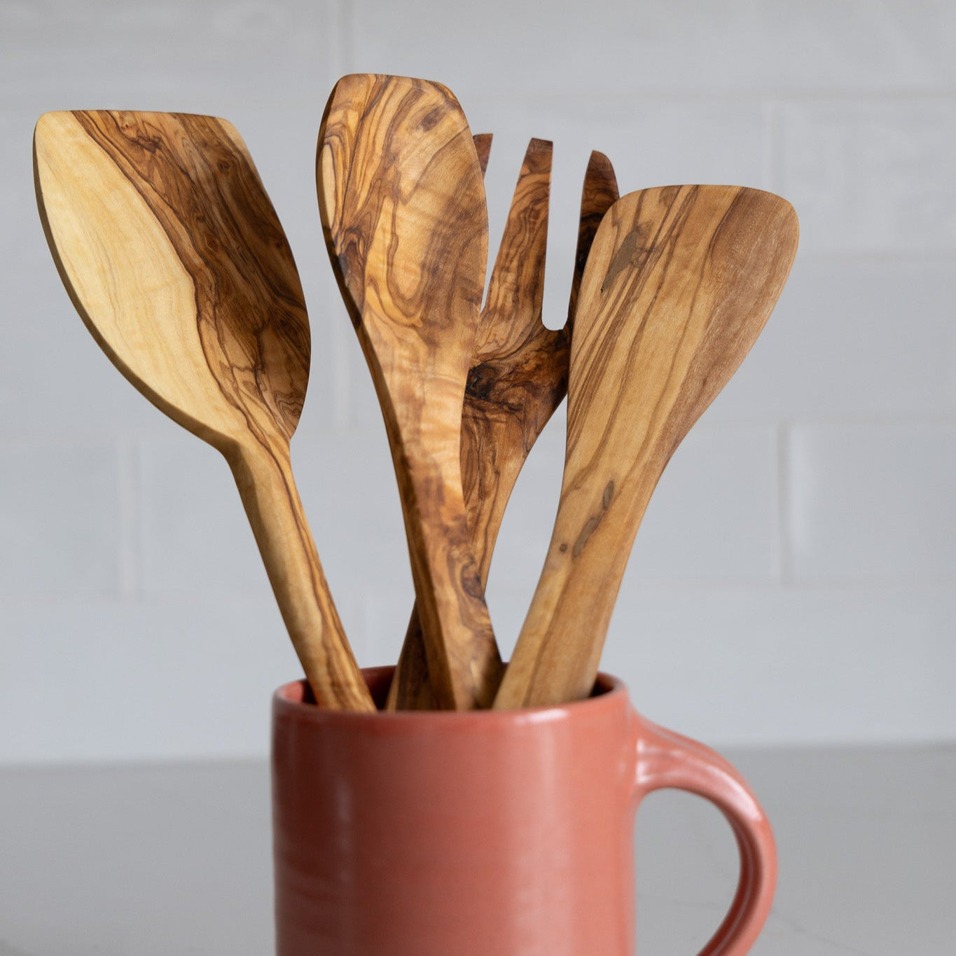A full collection of natural olive wood utensils, with two sizes of spatulas and serving spoon and fork