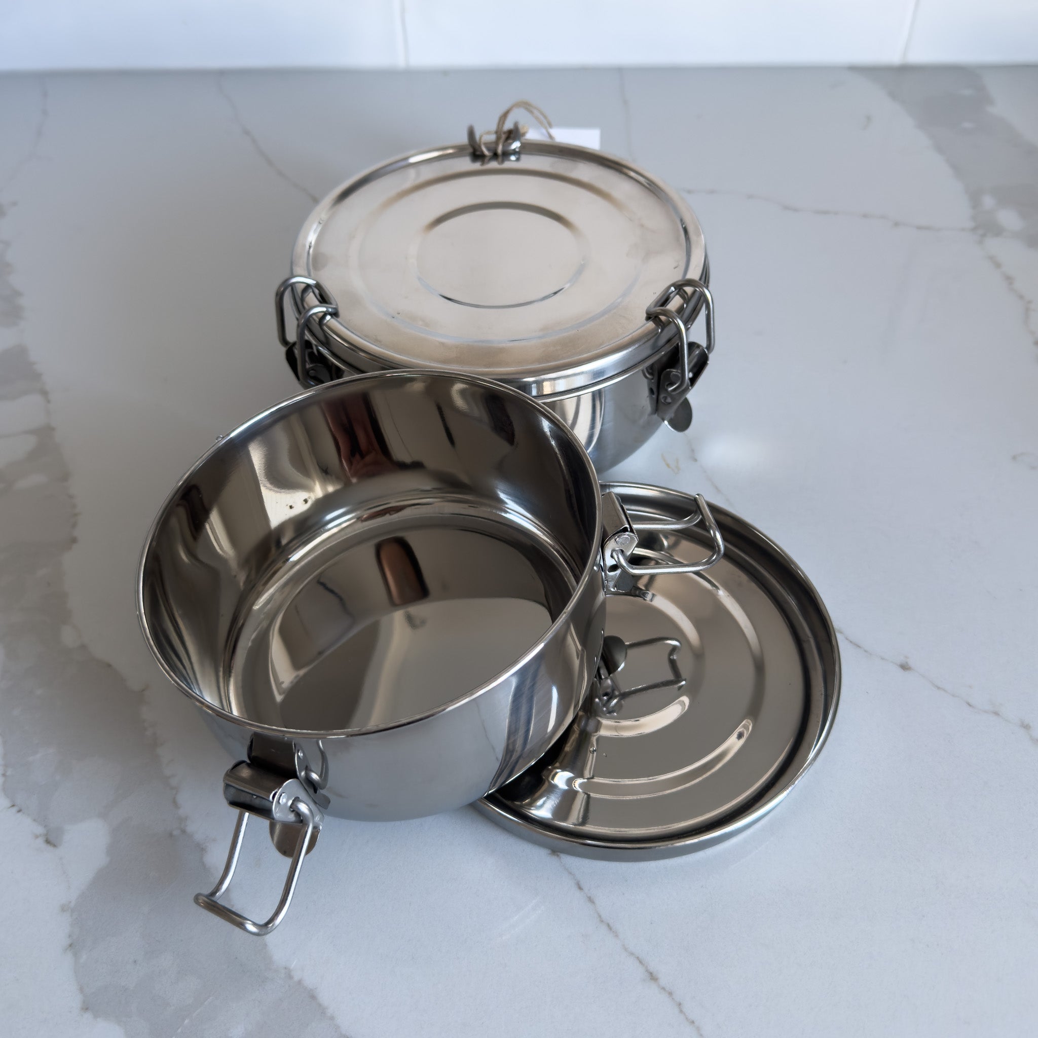 Two sizes of sustainable stainless steel food containers viewed from above with one open