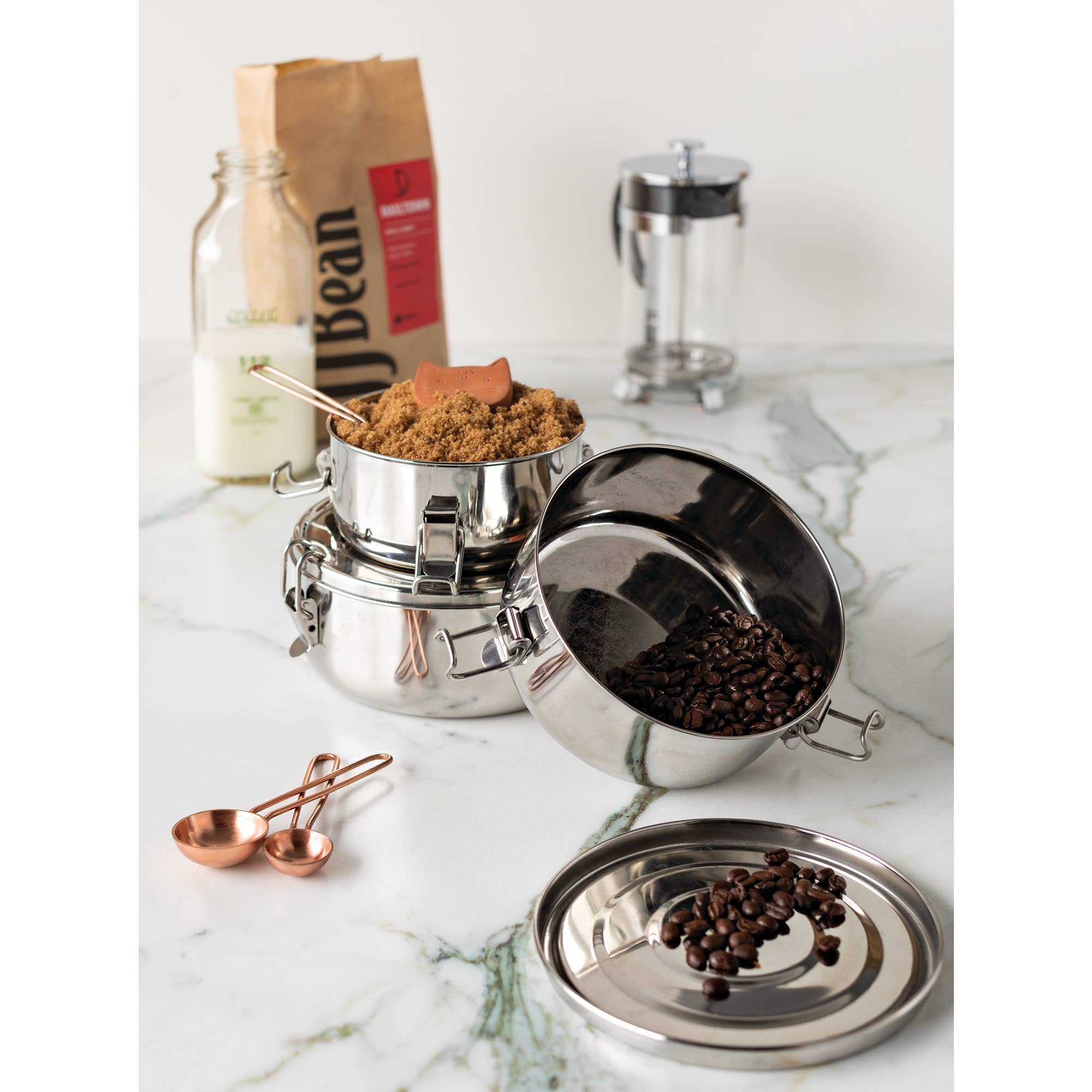 A variety of stainless steel food containers holding coffee beans and brown sugar