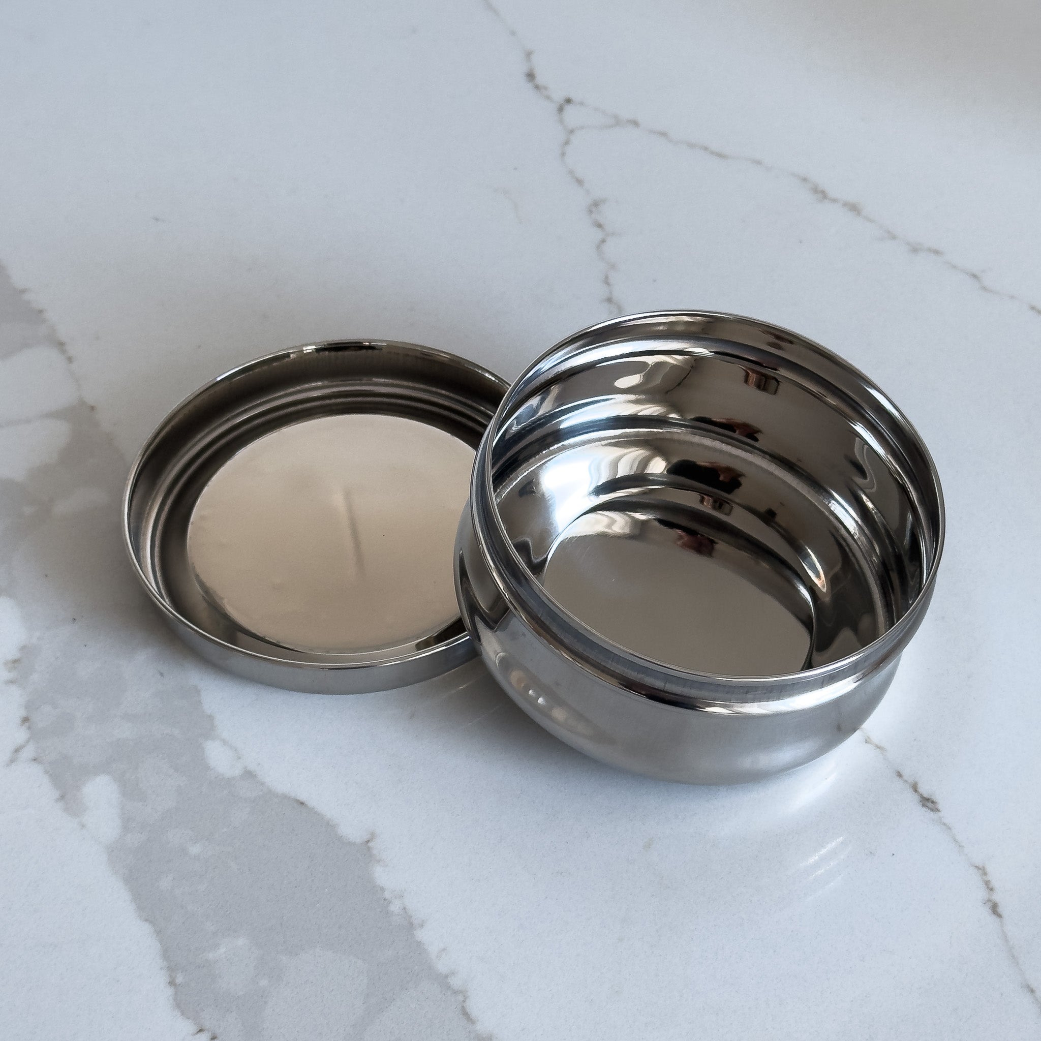 A small stainless steel snack container viewed from above with the lid off