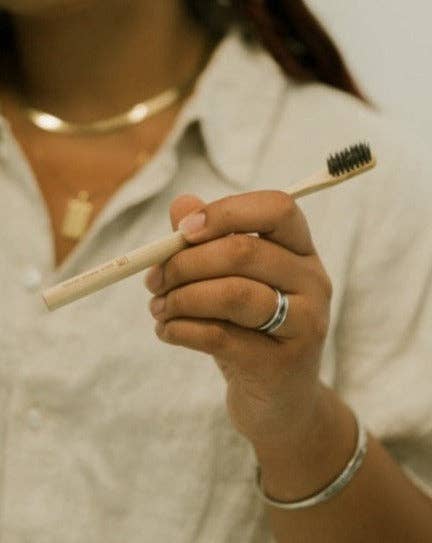 A person holding a bamboo toothbrush