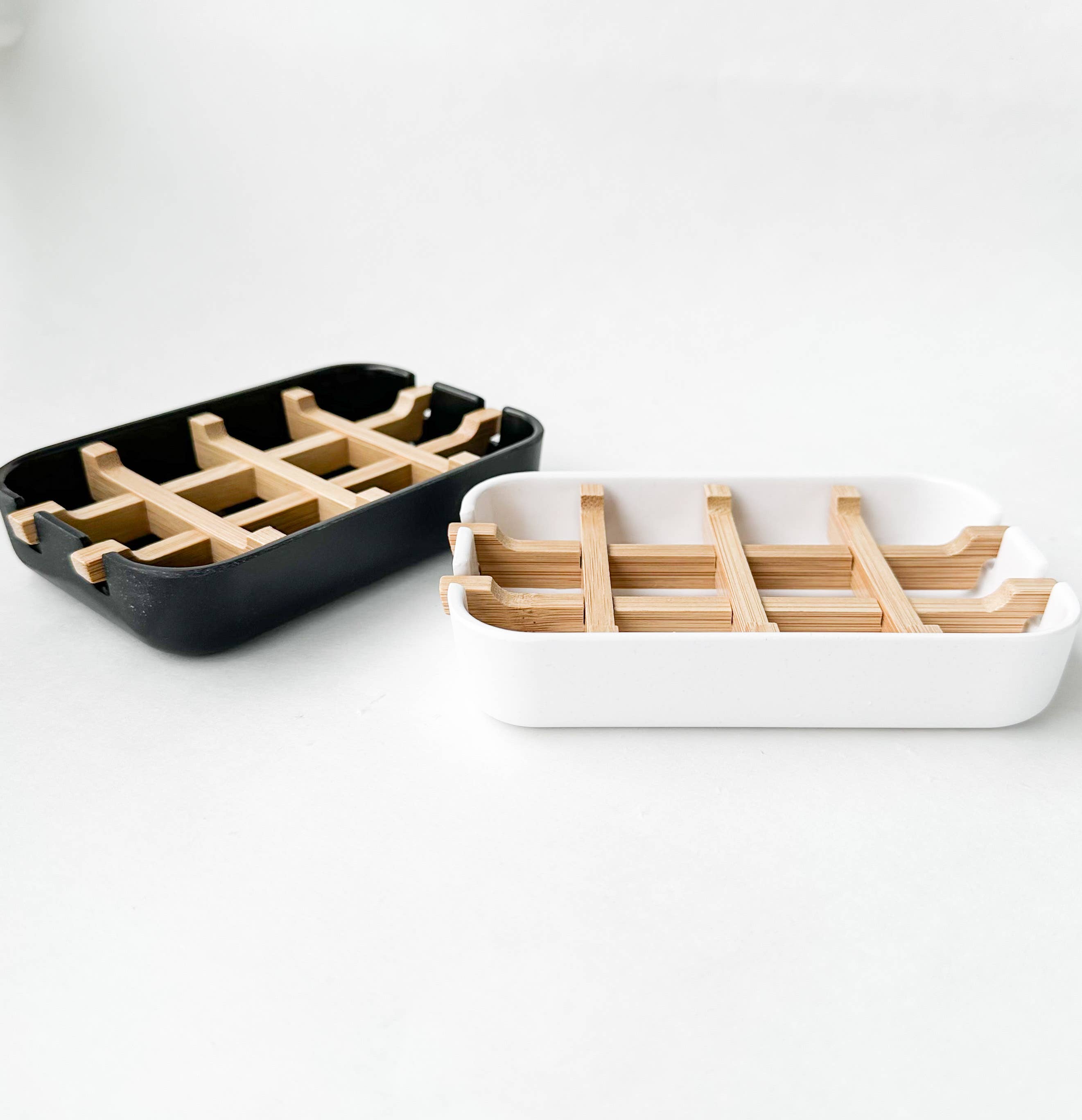 A side view of two biodegradable soap dishes, one black and one white