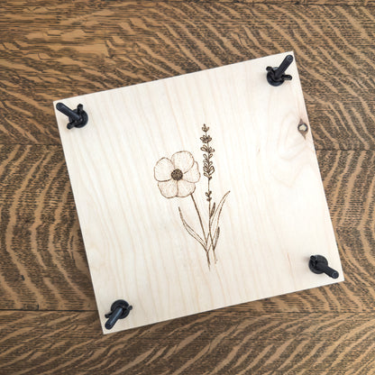 A handmade birch and cardboard flower press shown from above