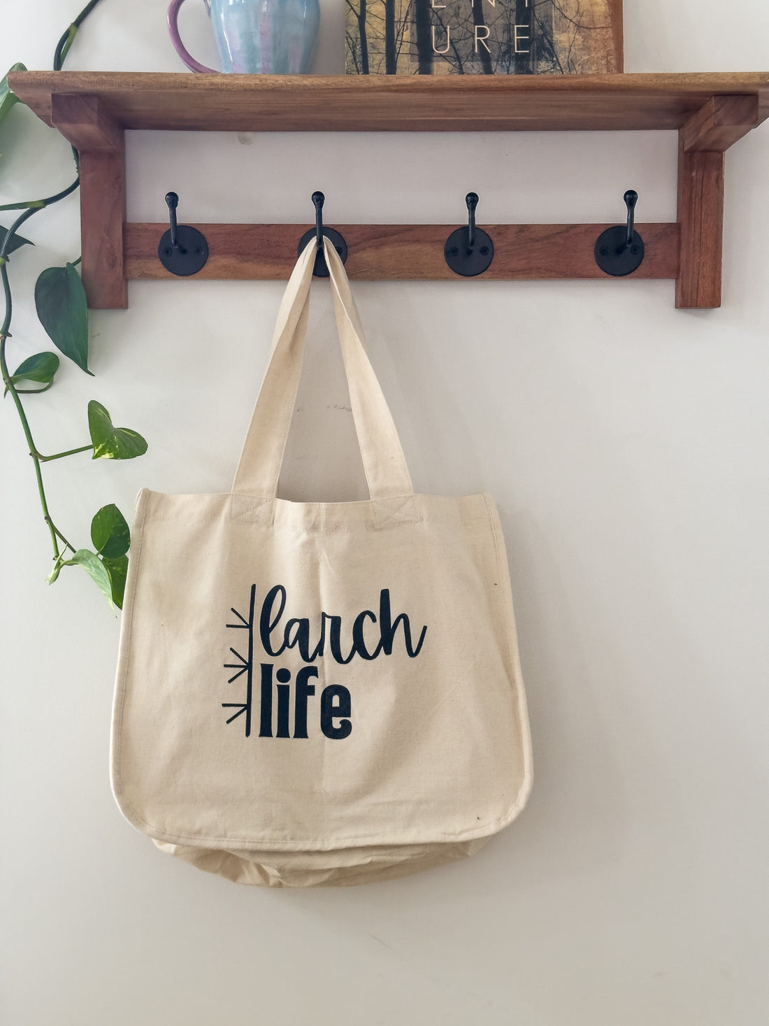 An eco-friendly Larch Life multi-pocket tote bag hangs on a hook