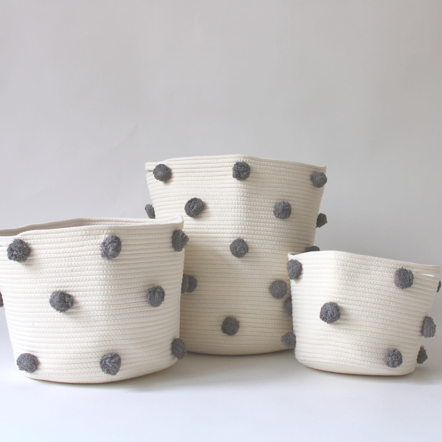 A trio of handmade cotton baskets with charcoal pom-poms