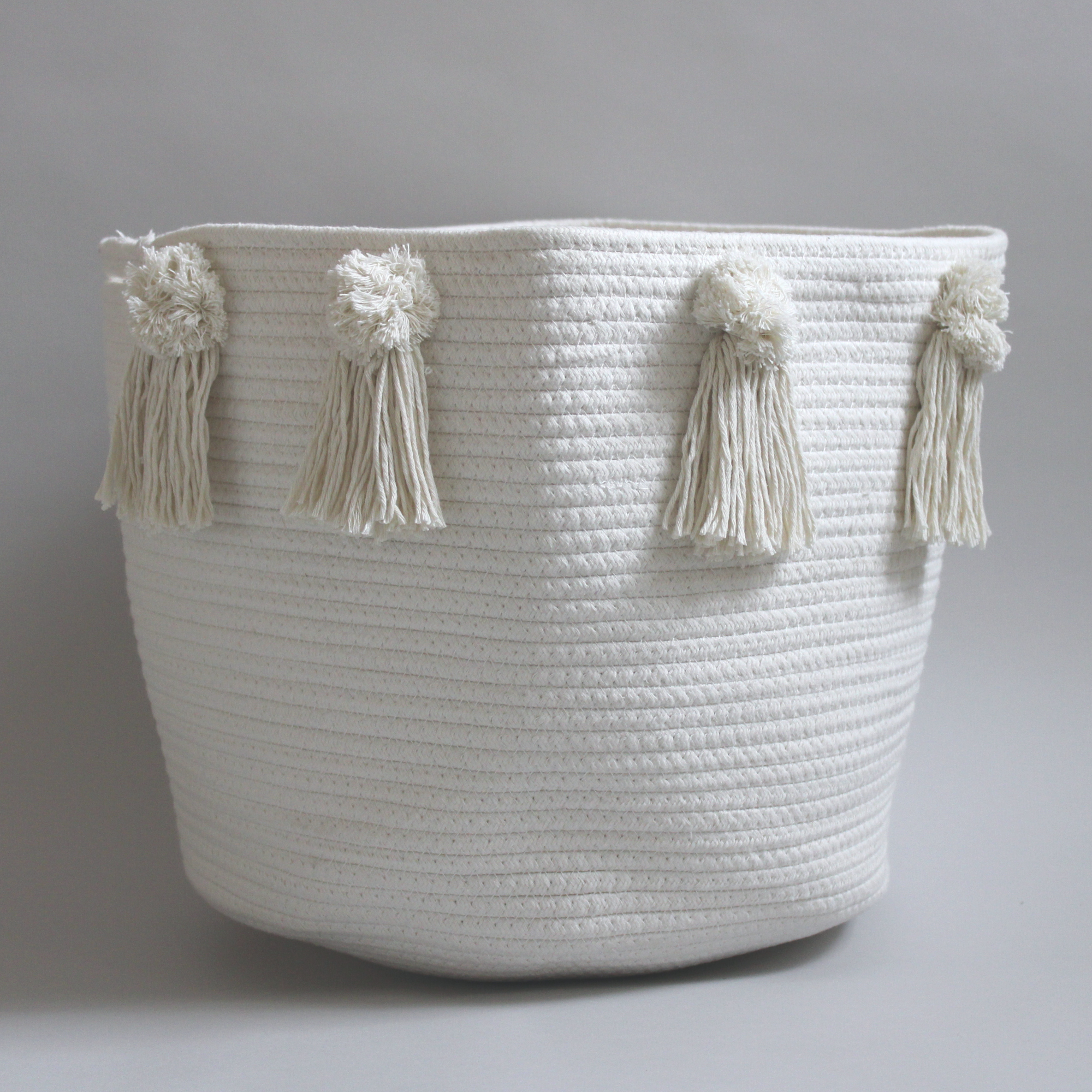 A large handmade cotton basket with pom-poms and tassles