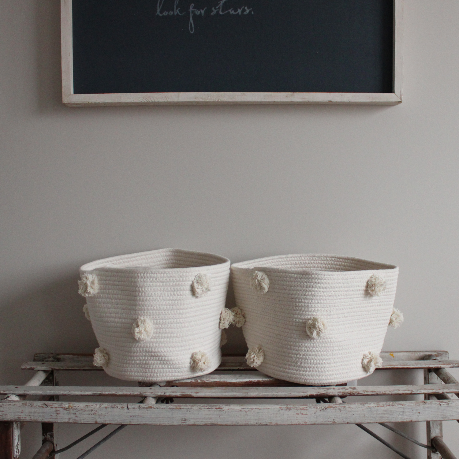 Two handmade natural cotton baskets sit on a bench