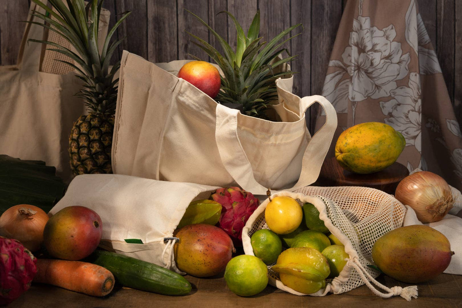 A cotton mesh produce bag holding a variety of fruits alongside other styles of bag