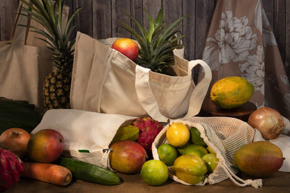 A cotton mesh produce bag holding a variety of fruits alongside other styles of bag