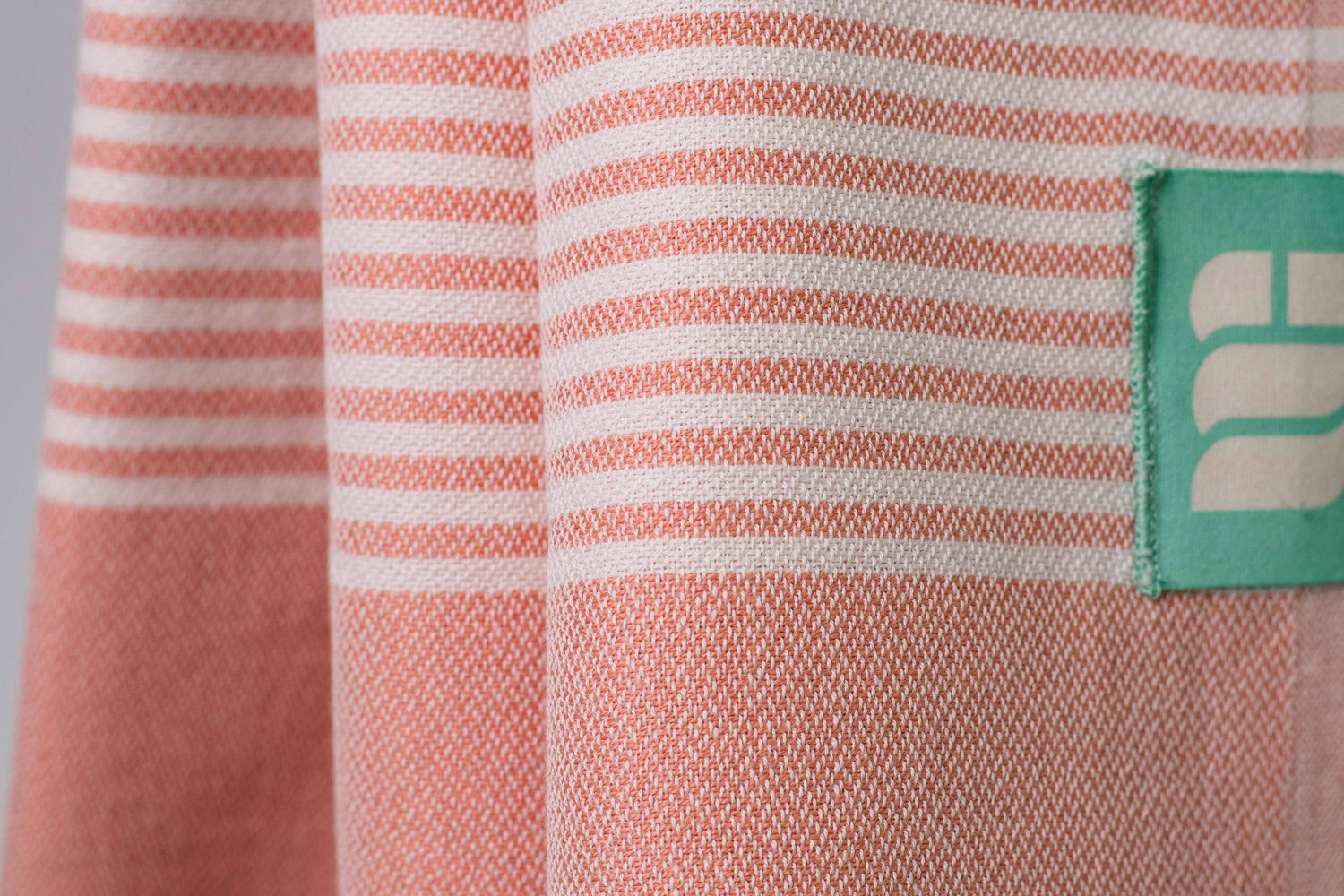 A close up of a salmon pink lightweight Turkish bath towel showing texture