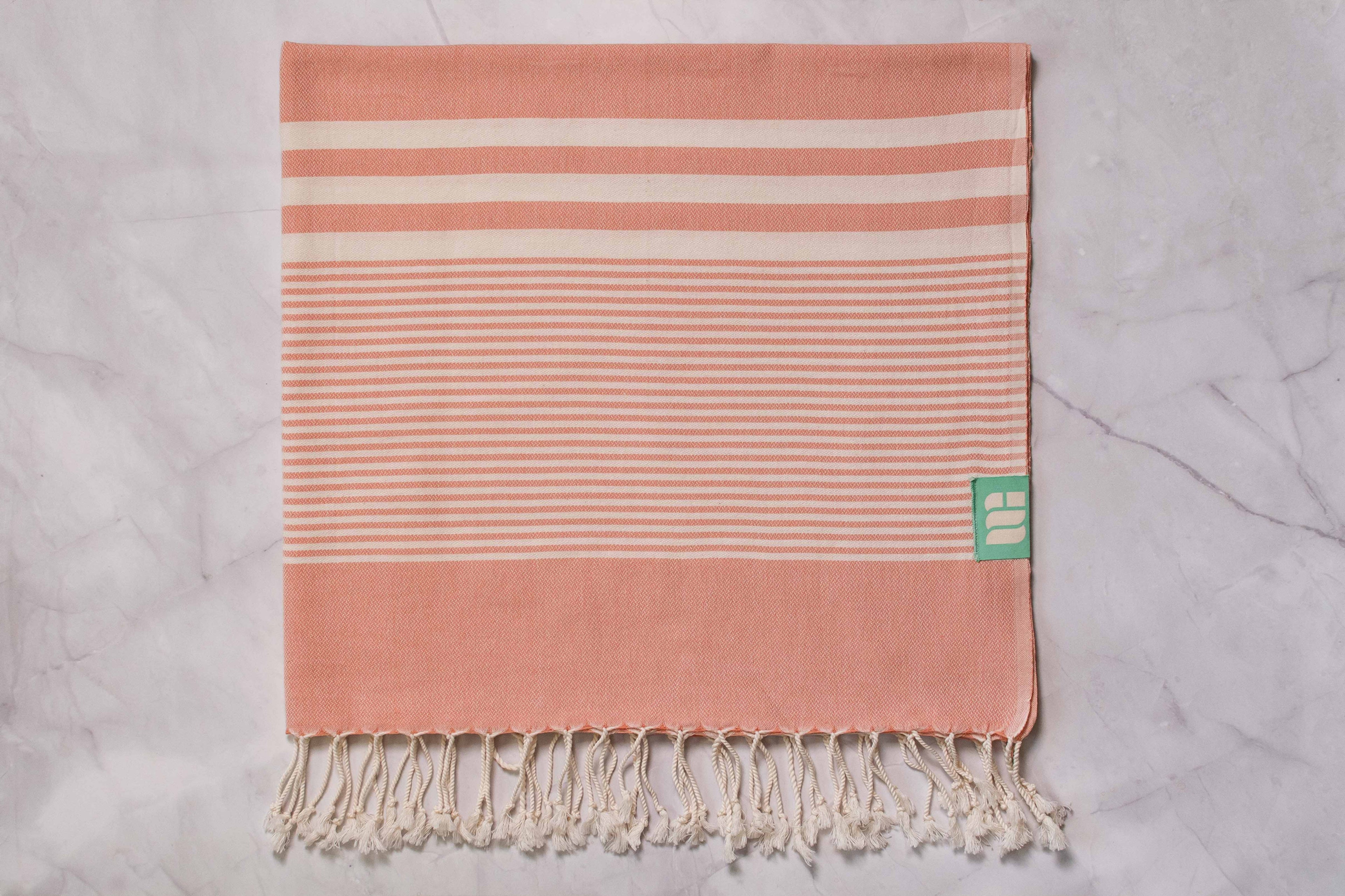 A salmon pink lightweight Turkish bath towel