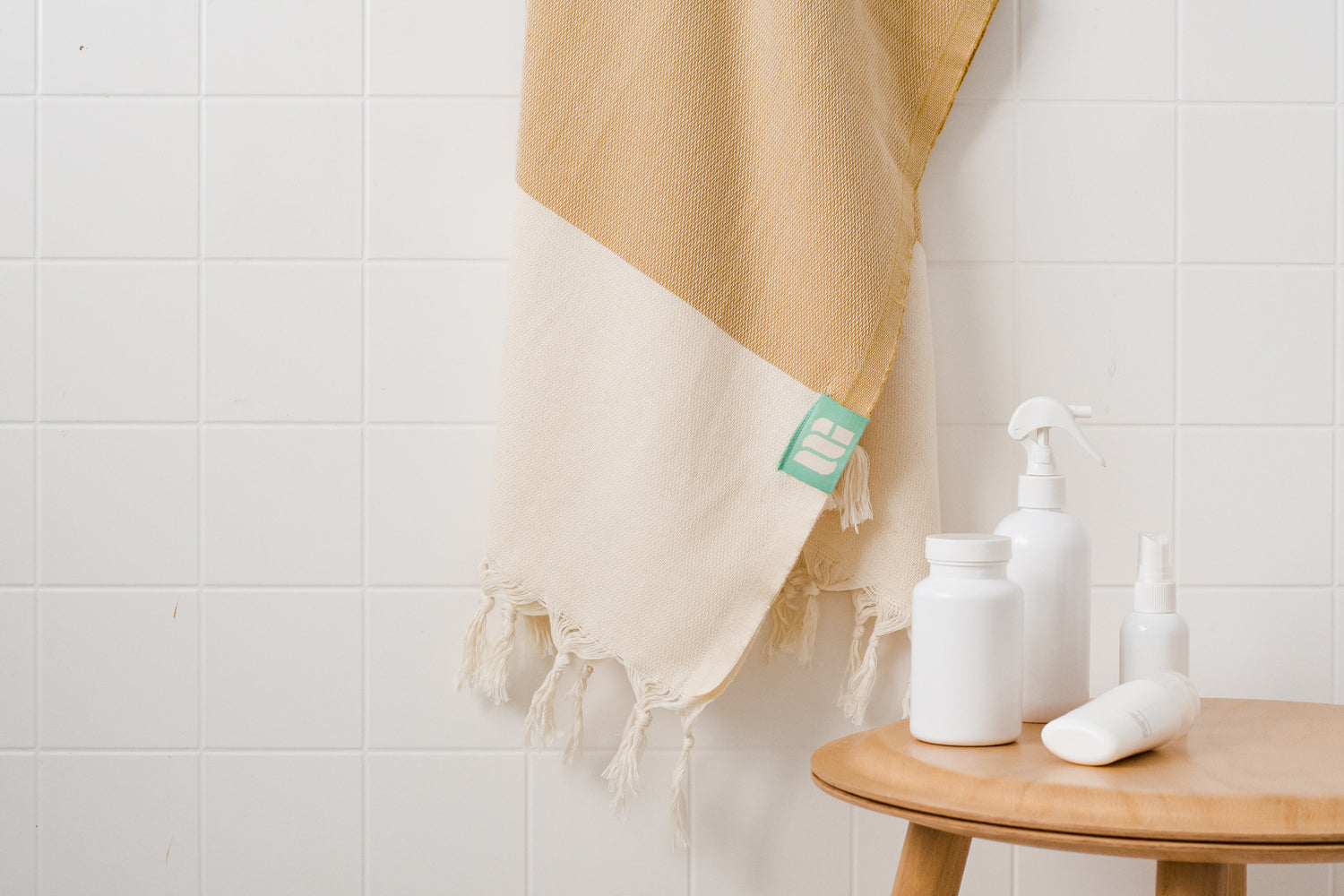 A mustard yellow Turkish bath towel hangs near bath products