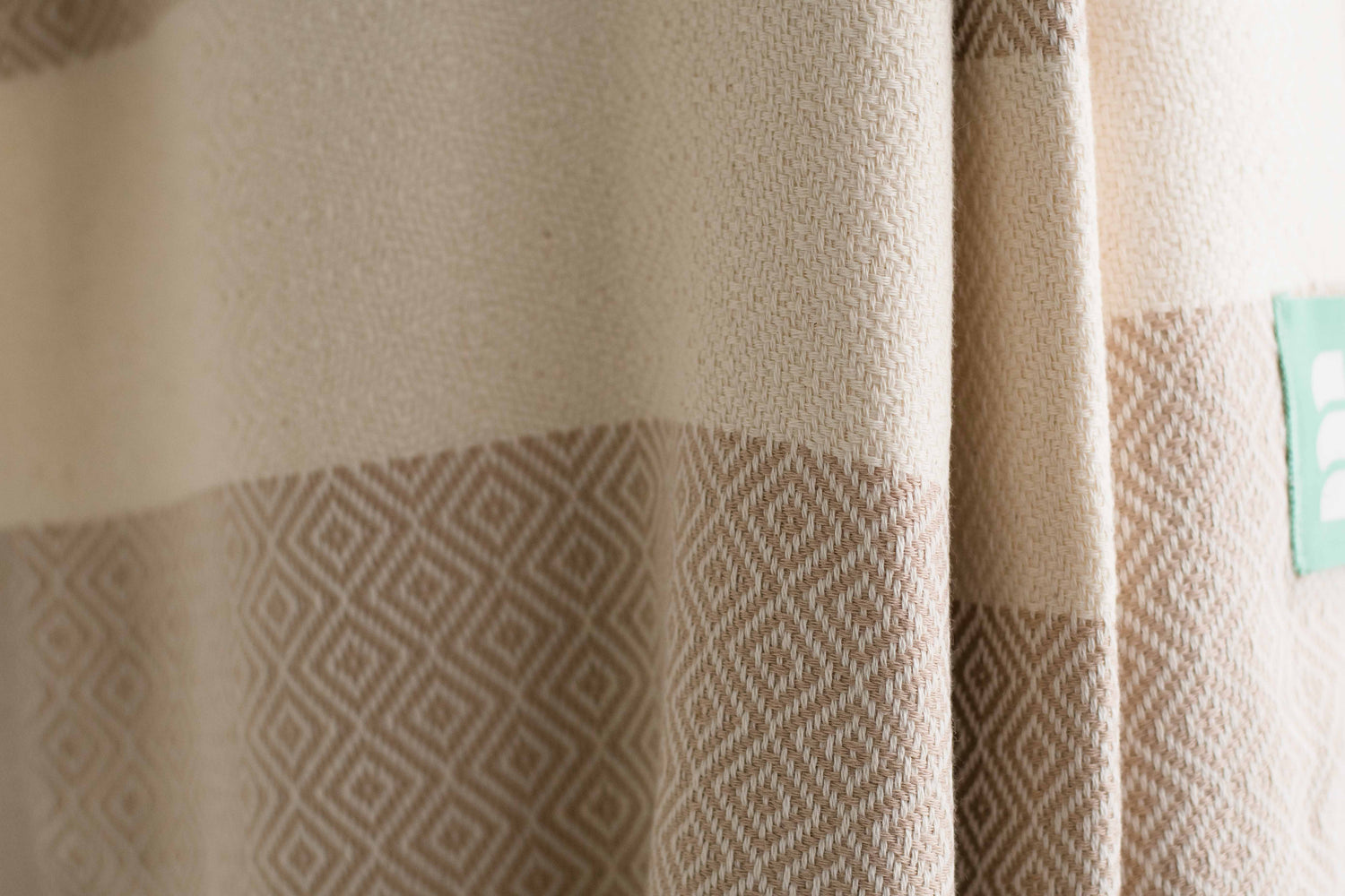 A close up of a beige heavy weight geometric patterned Turkish bath towel showing texture