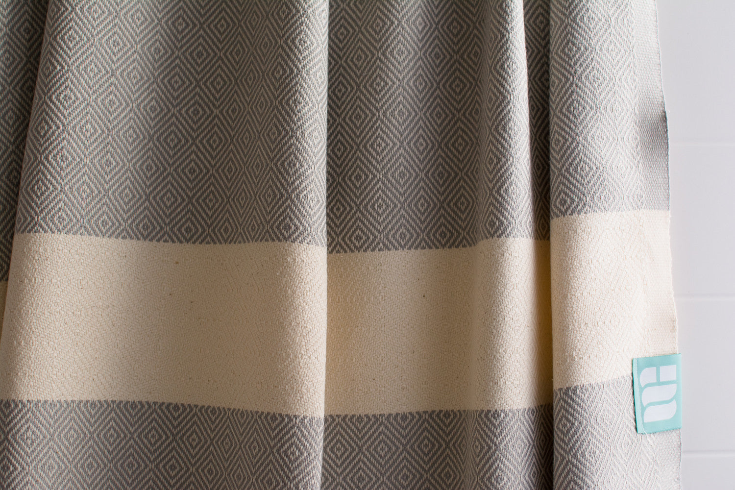 A close up of a light grey heavy weight geometric patterned Turkish bath towel showing texture