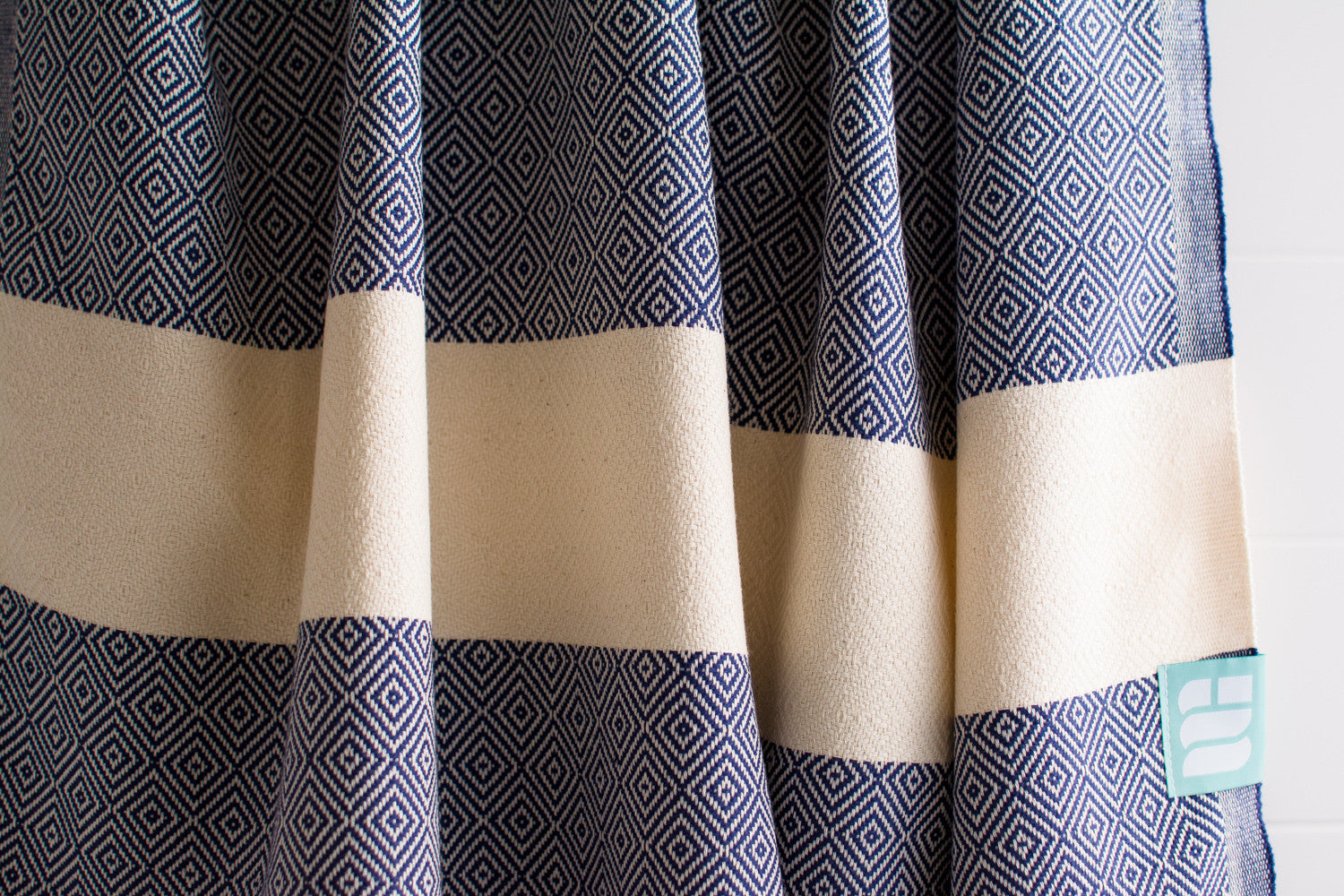 A close up of a navy blue heavy weight geometric patterned Turkish bath towel showing texture