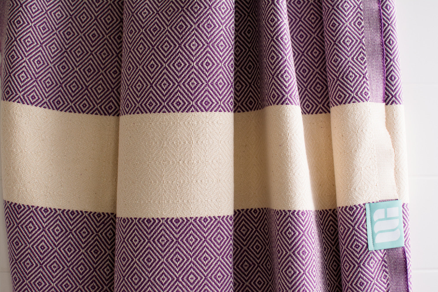 A close up of a purple heavy weight geometric patterned Turkish bath towel showing texture