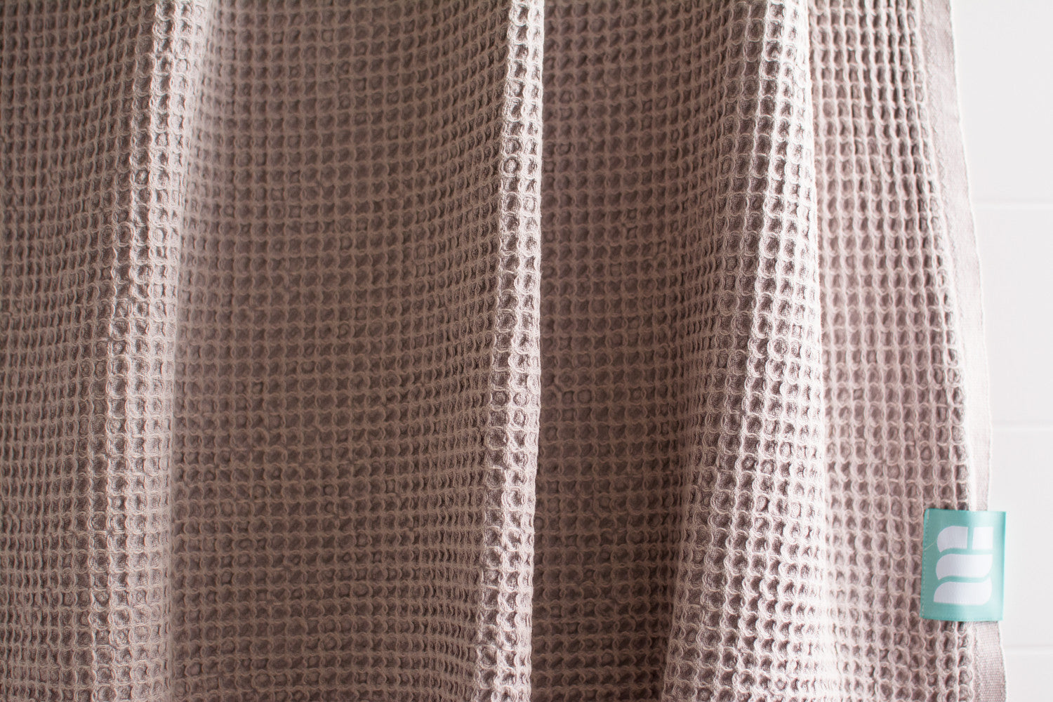 A close up showing the waffle texture of a natural cotton Turkish bath towel in beige