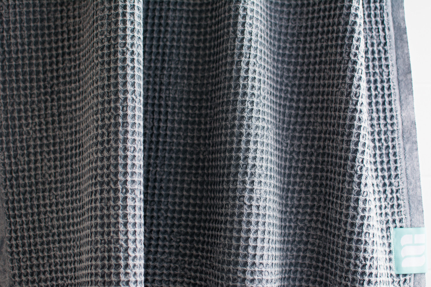 A close up showing the waffle texture of a natural cotton Turkish bath towel in blue