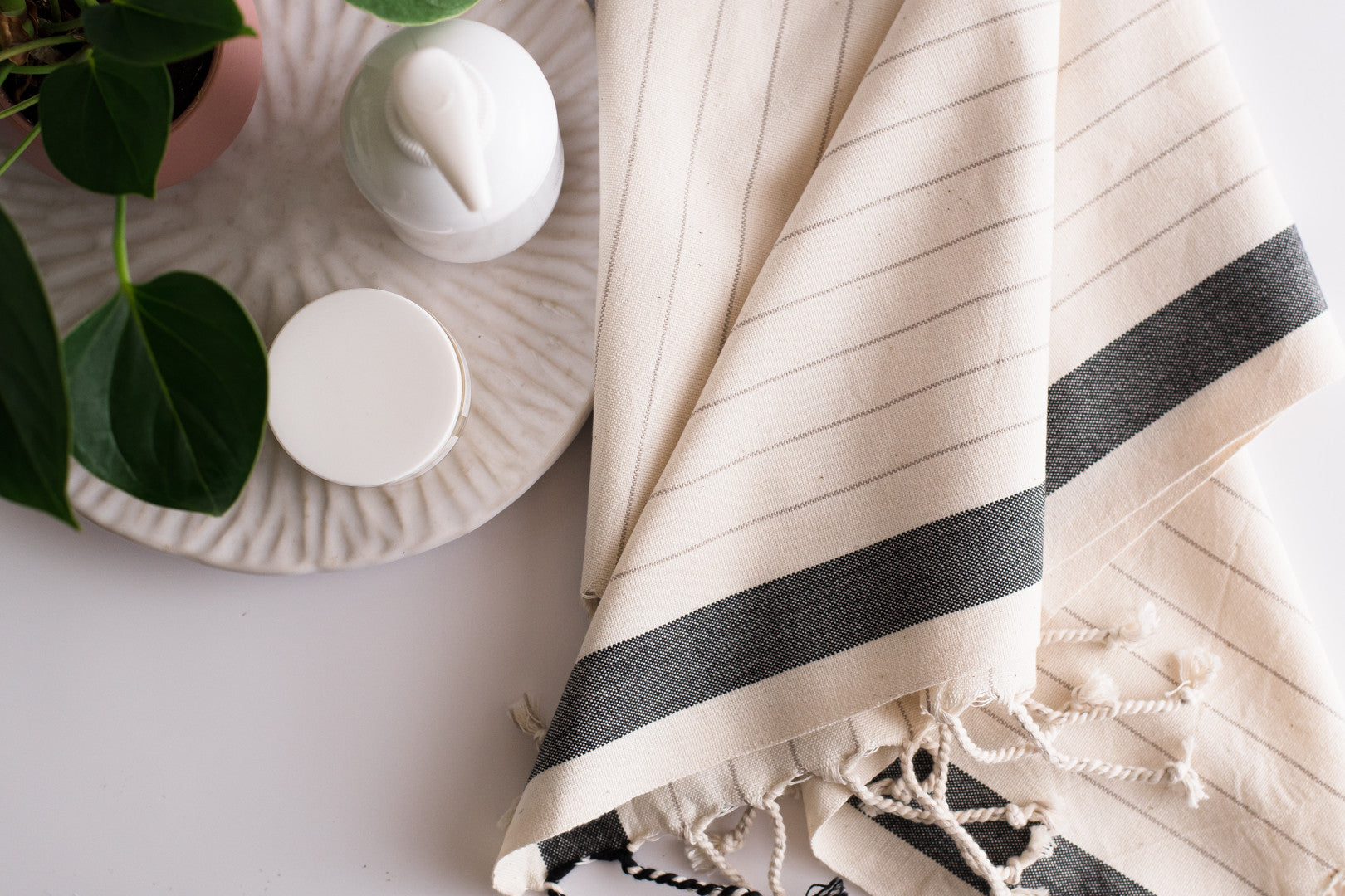 A natural cotton Turkish hand towel with bath products nearby