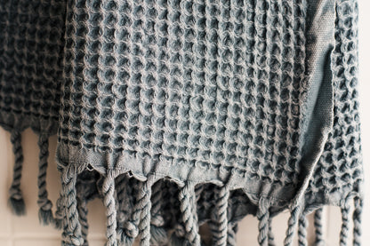 A close up showing the waffle texture of a natural cotton Turkish hand towel in blue