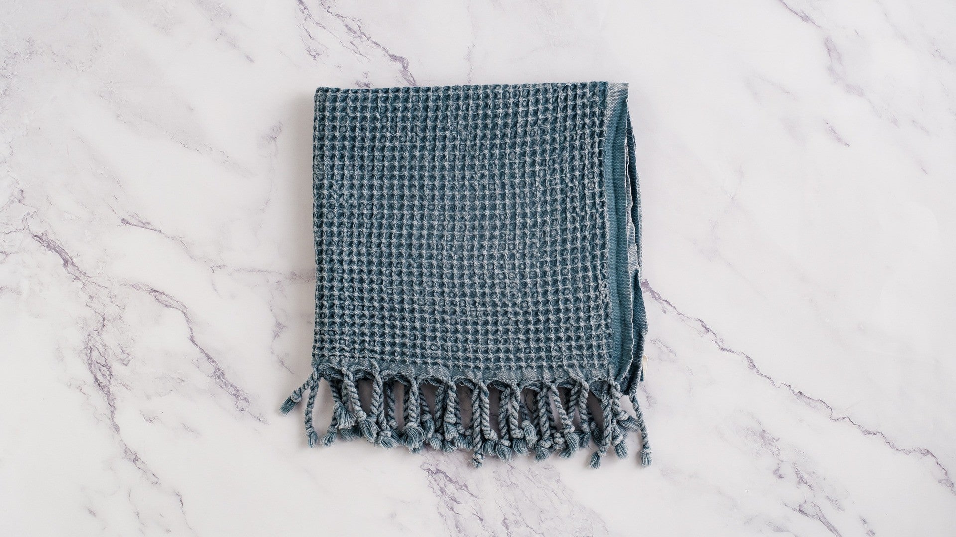 A waffle texture of a natural cotton Turkish hand towel in blue