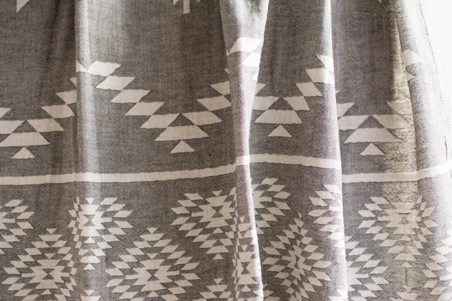 A close up of a medium weight Turkish bath towel in grey with geometric pattern showing texture