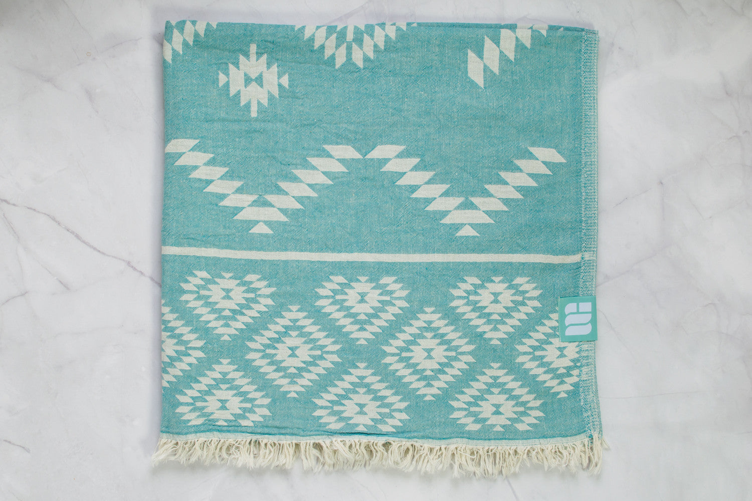 A medium weight Turkish bath towel in teal with geometric pattern