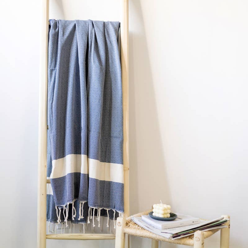 A blue natural cotton Turkish towel hangs on a ladder