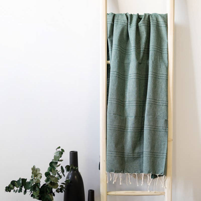 A natural cotton Turkish towel hangs on a ladder