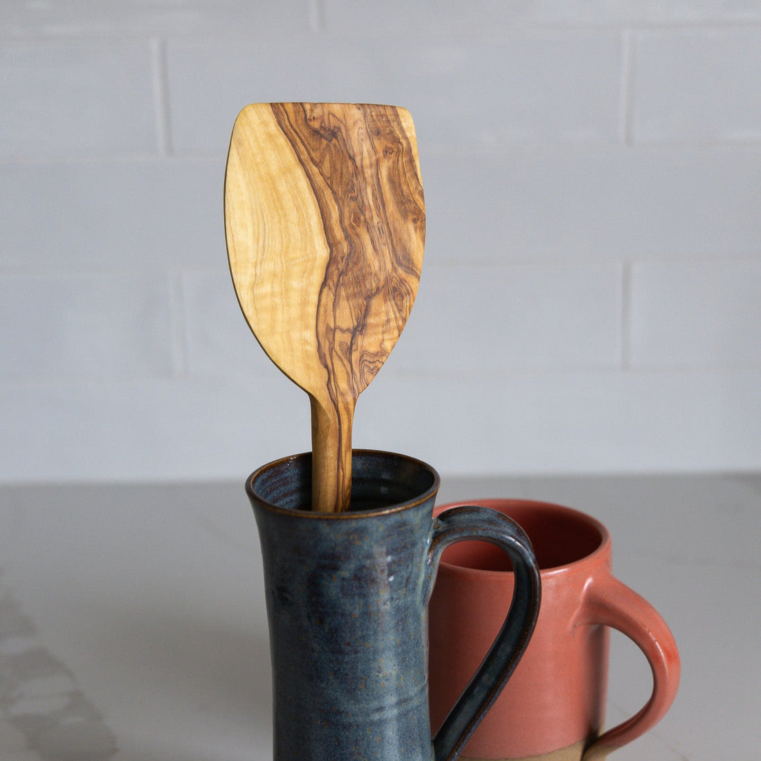 An oversized pancake spatula made of natural olive wood