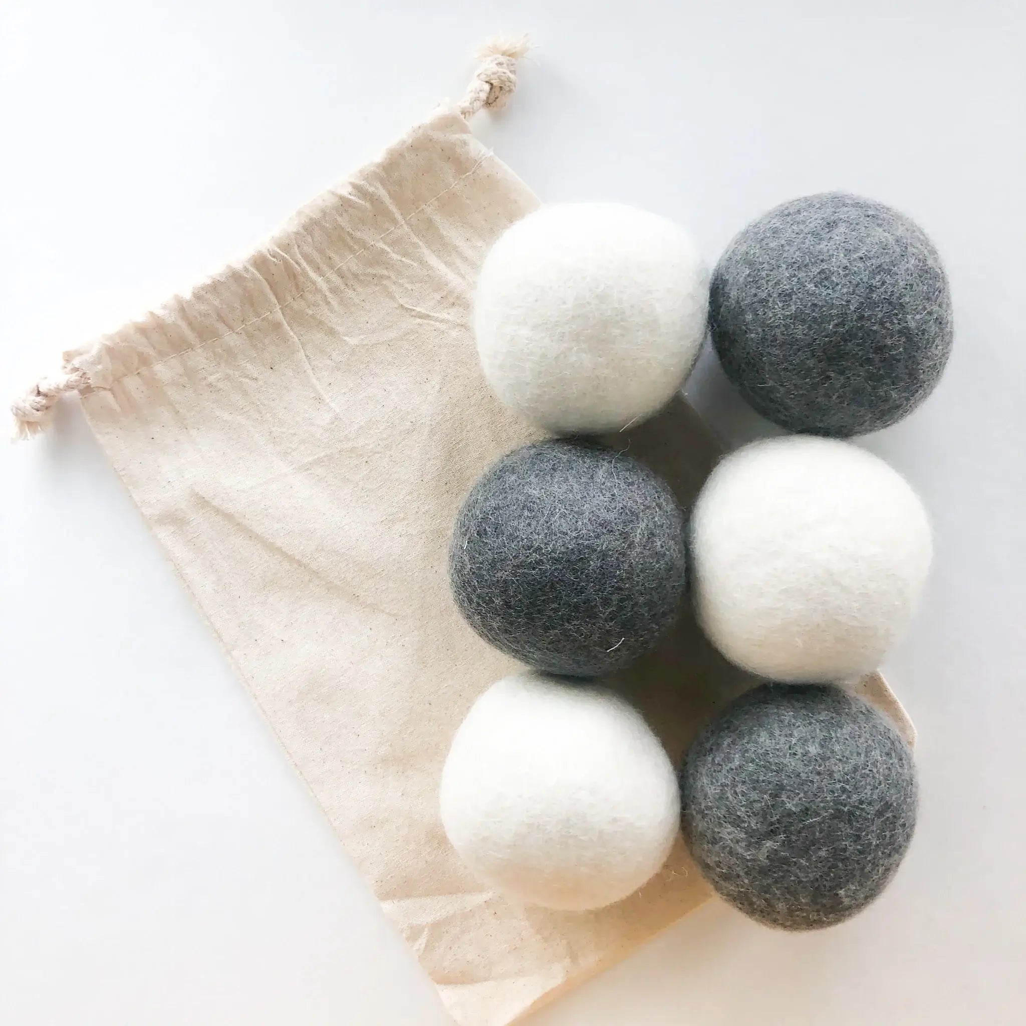 Six wool dryer balls sitting on the included storage bag