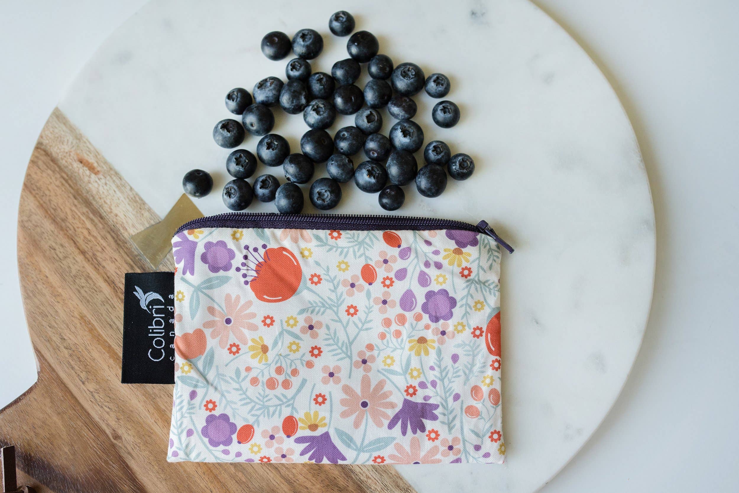 Blueberries  and a small reusable zip bag in made of a flower-motif fabric on a marble platter