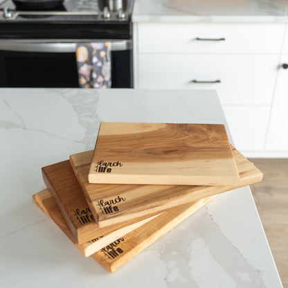 Set of wooden cutting boards with engraved text on a kitchen counter.