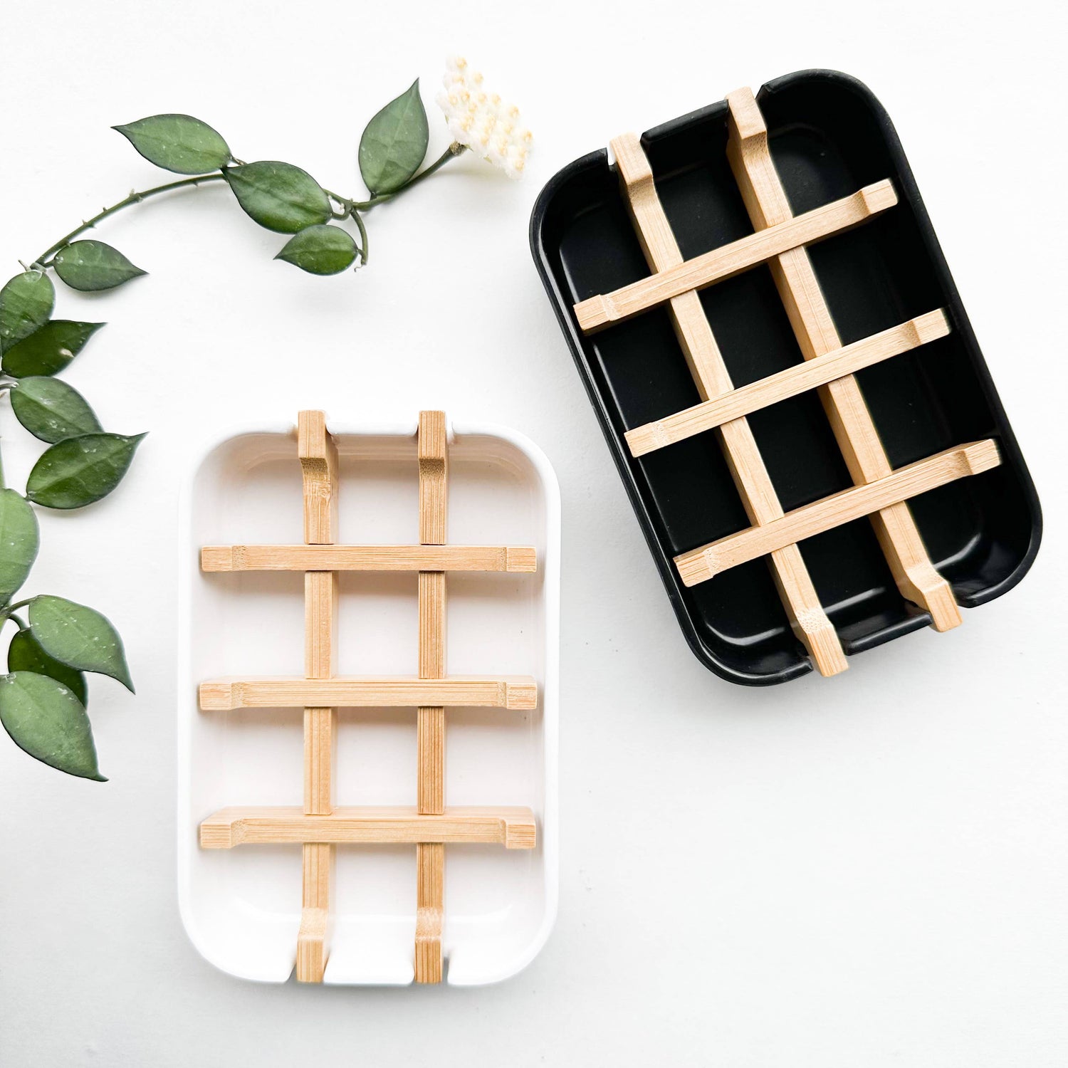 Two biodegradable corn starch and bamboo soap dishes, one in white and one in black