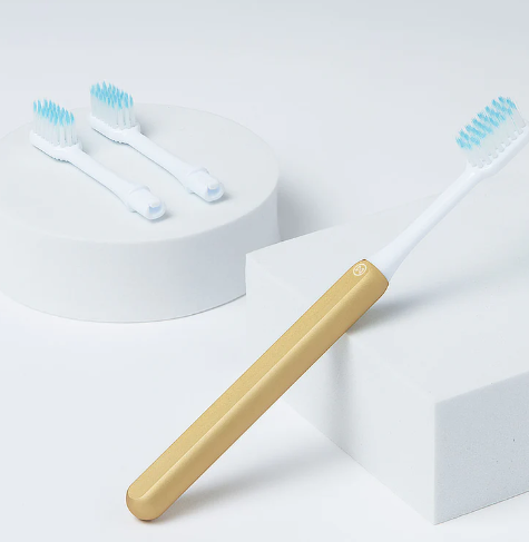 A sustainable Nada kid-size toothbrush with gold anodized handle