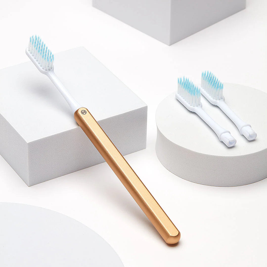 A sustainable Nada toothbrush with gold anodized handle