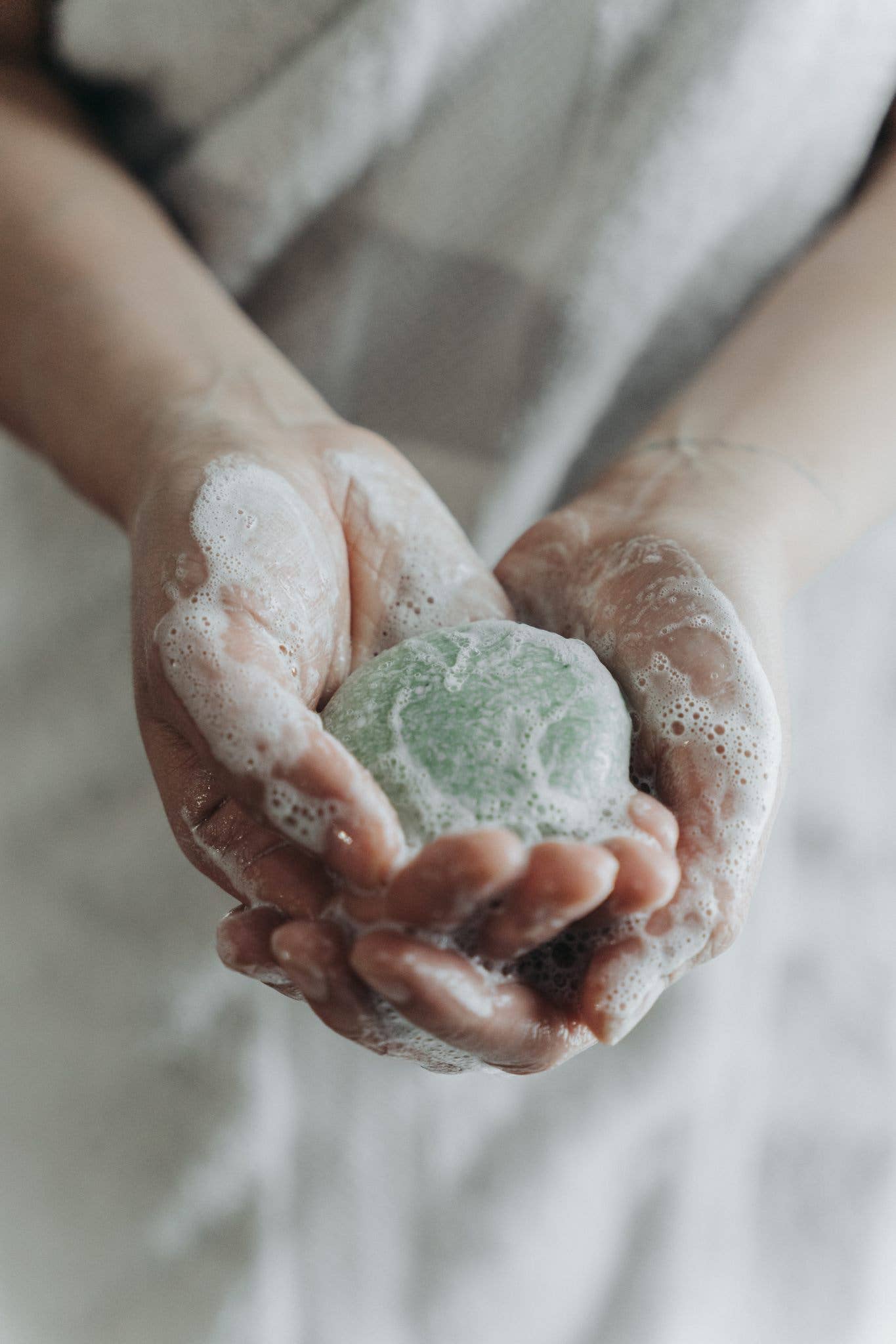 A person holds a sustainable solid shampoo bar in their cupped hands