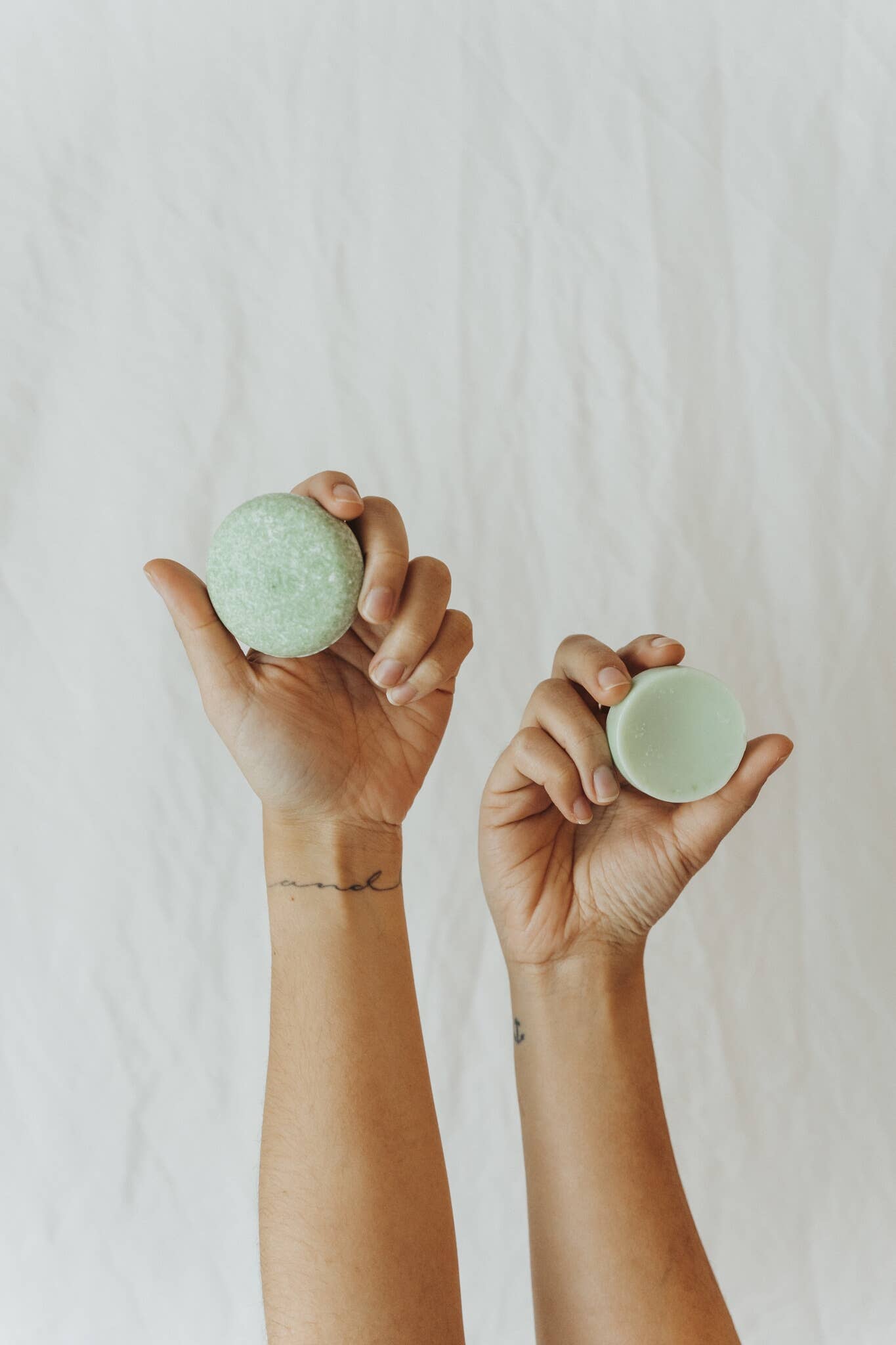 Hands hold up a sustainable solid shampoo bar and conditioner bar