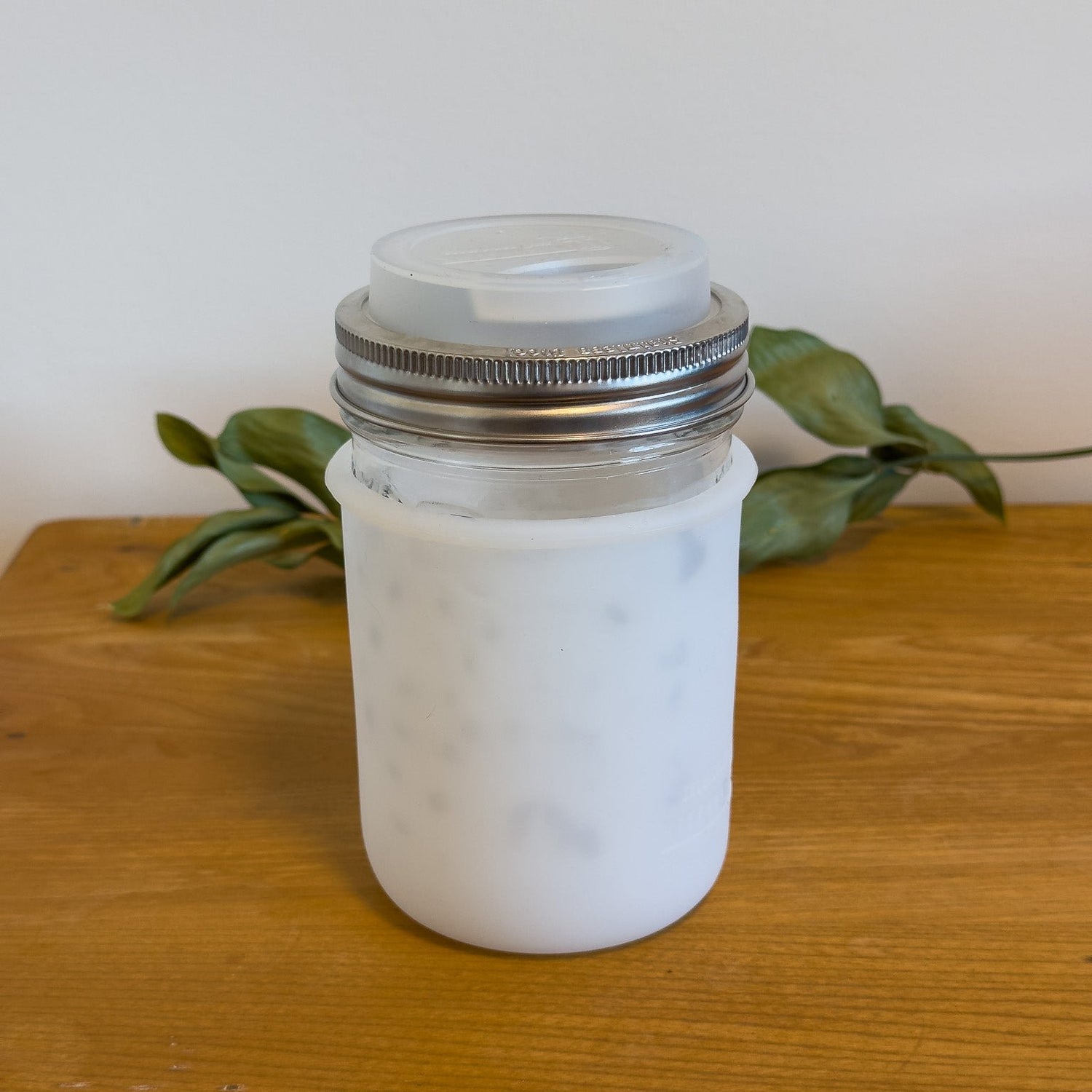 A wide-mouth mason jar with silicone sleeve and travel lid