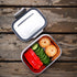 A stainless steel bento box holding a variety of produce