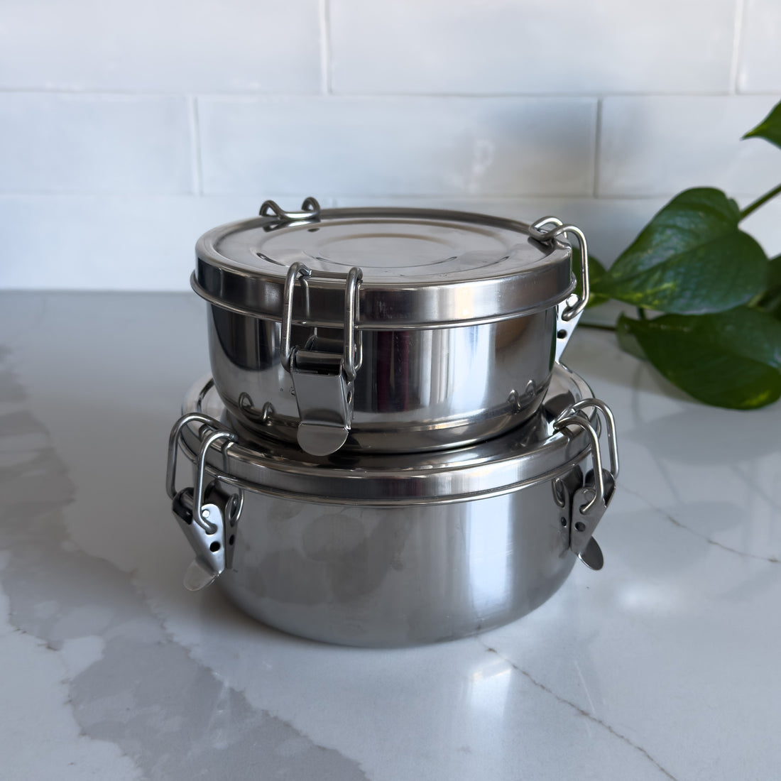 Two sizes of sustainable stainless steel food containers with one stacked on top of the other